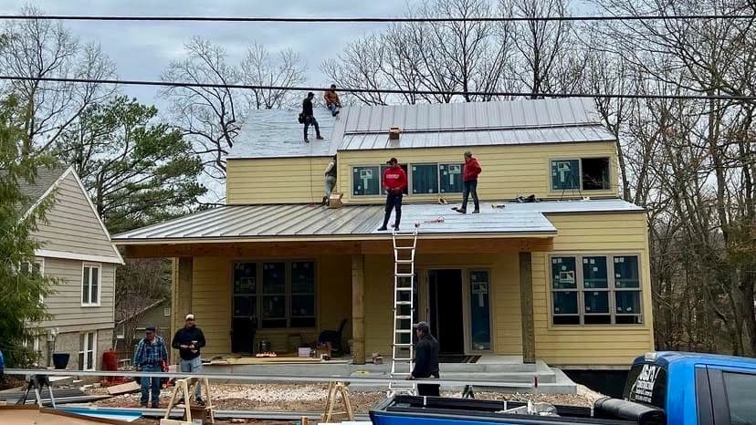 Image of one of our crews on the roof of a house installing metal roofing